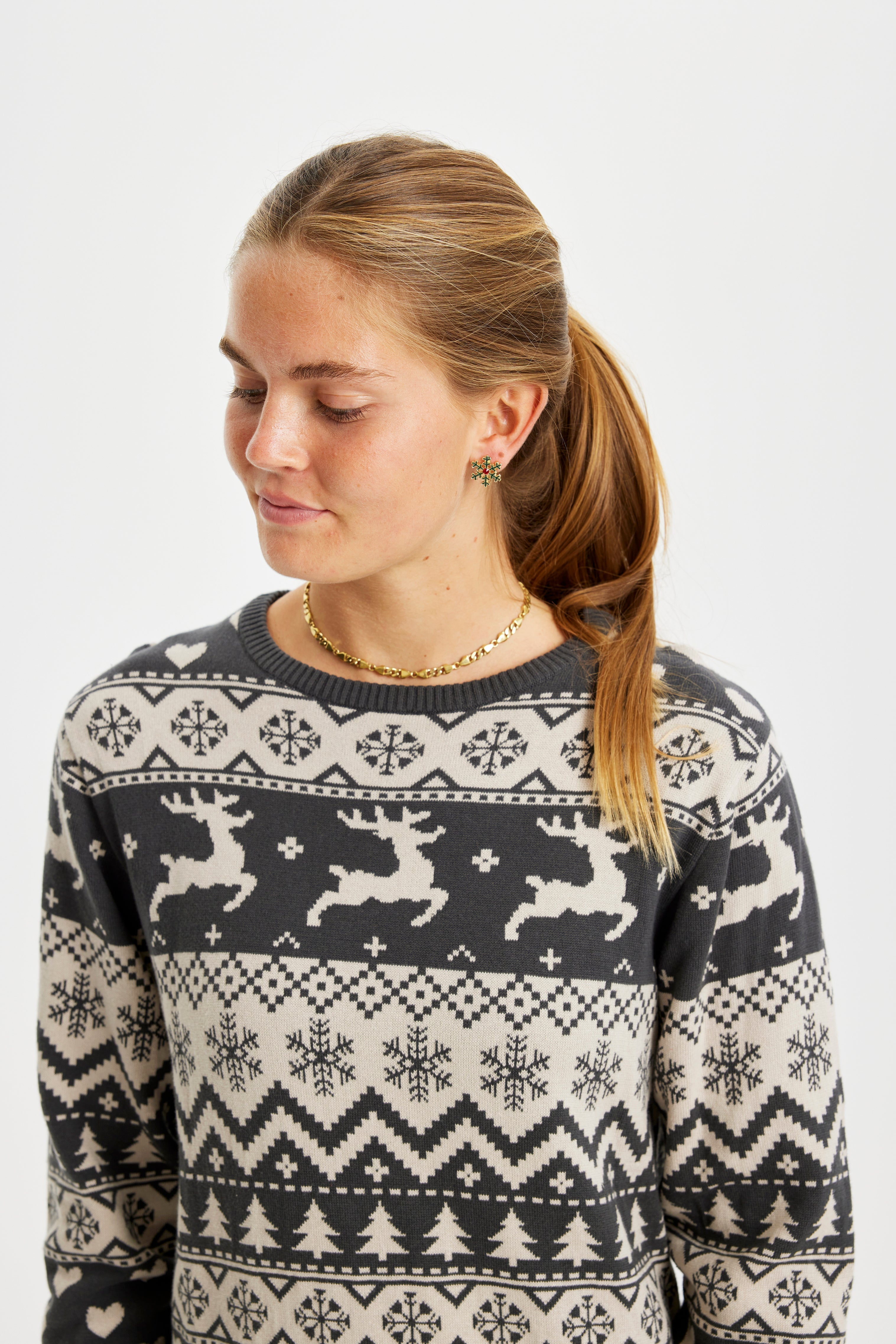 Een vrouw kijkt naar beneden terwijl ze een grijze kerstjurk draagt.